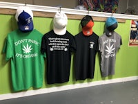 four t - shirts hanging on a green wall